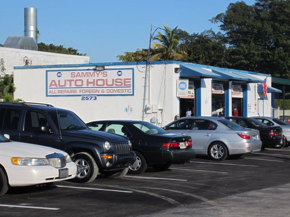 A white auto repair building displays a large 'Sammy's Auto House' sign with several cars parked in front.